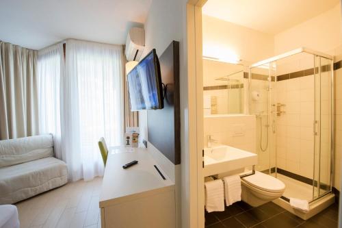 卢加诺Hotel Delfino Lugano的一间带水槽和卫生间的浴室以及一台电视。