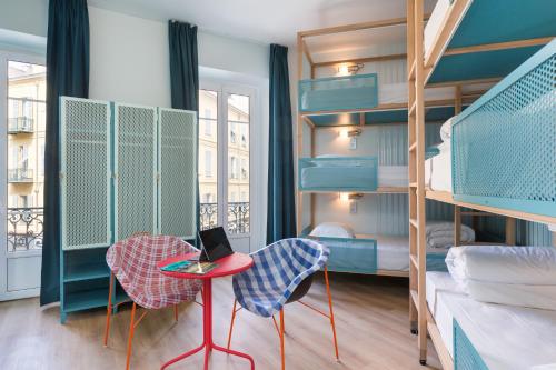 尼斯Hostel Ozz Nice的客房设有双层床和一张带笔记本电脑的桌子。