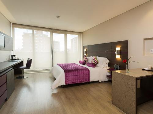 波哥大美居波哥大BH佐纳金融酒店的一间卧室配有一张大床和紫色毯子