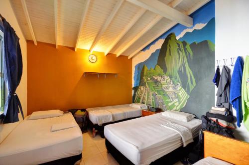 麦德林The Wandering Paisa的一间设有三张床的客房,墙上挂着壁画