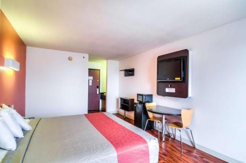 兰辛兰辛南芝加哥6号汽车旅馆的一间酒店客房,配有一张床铺、一张桌子和一台电视