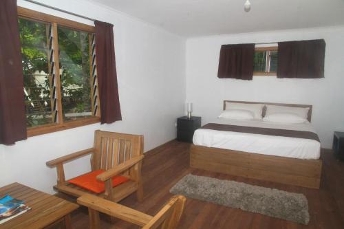 HalisiEvis Resort at Nggatirana Island的卧室配有床、椅子和窗户。