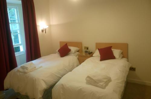 哈雷克Byrdir House的客房设有2张带白色床单和红色枕头的床。
