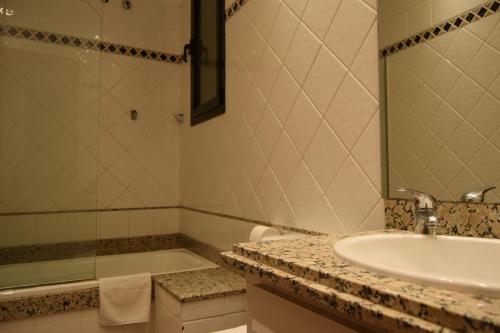 赫罗纳历史公寓酒店的一间带水槽、浴缸和镜子的浴室