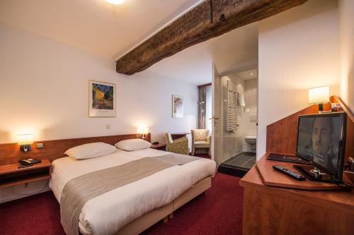 马斯特里赫特登霍夫餐厅酒店的一间卧室配有一张大床和电视