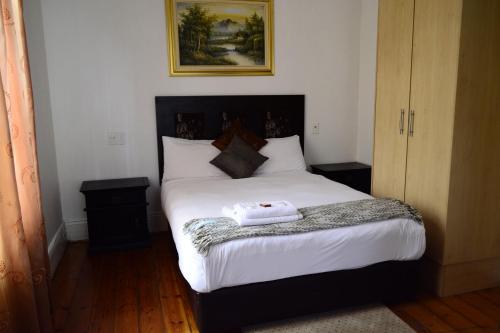 德班拉勒萨旅馆的一间卧室配有一张带白色床单的大床