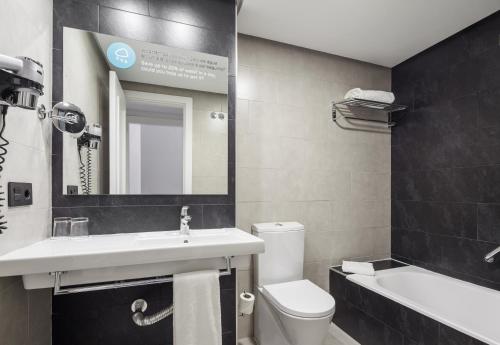 马德里马德里伊鲁尼套房酒店的浴室配有盥洗盆、卫生间和浴缸。