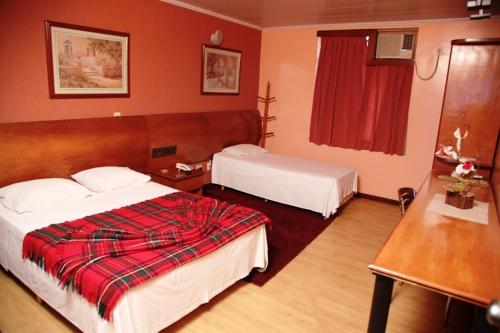 塔瓜汀加Atlas Hotel Residence的酒店客房设有两张床和红色的墙壁。