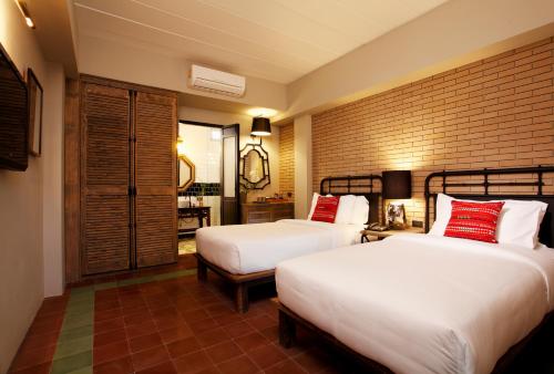 曼谷班查特酒店的一间卧室设有两张床和砖墙