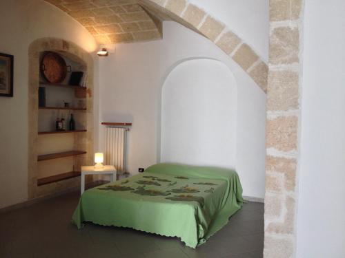 滨海波利尼亚诺Dimora Tarantini的一间卧室配有一张绿色的床和一张桌子