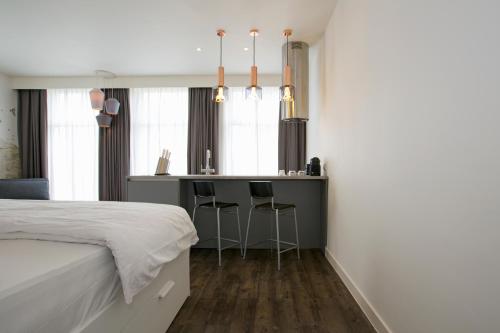 鹿特丹德维特一室公寓的一间卧室配有一张床,酒吧配有凳子