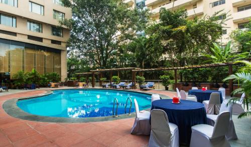 班加罗尔大法官法庭酒店的一座带桌椅的游泳池位于大楼旁
