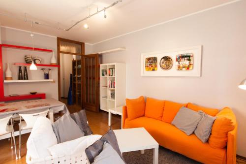 乌迪内Toti Apartment的客厅配有橙色沙发和桌子