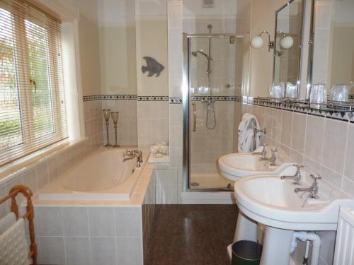伊斯特布恩The Manse B&B的浴室配有2个盥洗盆、浴缸和淋浴。