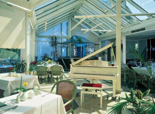 滕普林法瑞库格酒店的餐厅的白色钢琴,配有桌椅