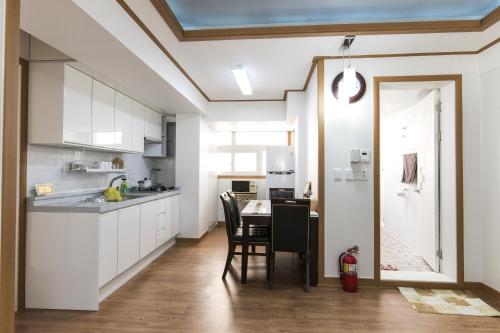 首尔克里宾馆的厨房配有白色橱柜和桌椅