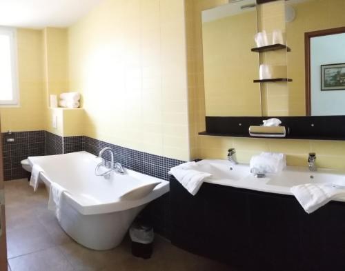 Bélesta帕莱斯卡特里酒店的浴室设有2个水槽、浴缸和镜子