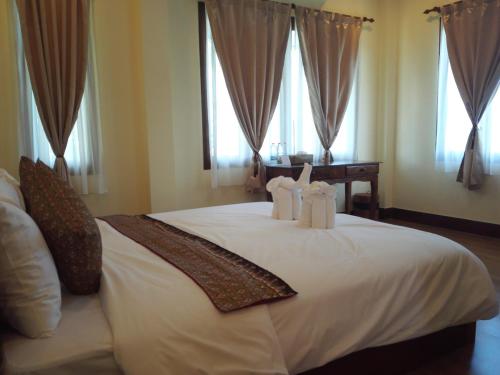董里班布萨巴酒店的一间卧室配有一张带白色床单和窗户的床。