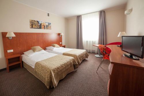 克拉科夫Hotel Major Budget的酒店客房设有两张床、一张桌子和一台电视。