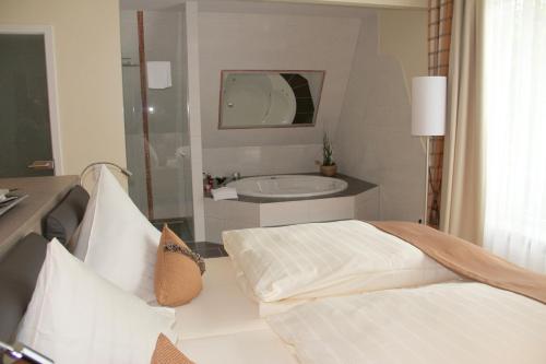 沃尔姆斯安什洛斯帕克别墅酒店的一间卧室配有一张床和一个水槽和一个浴缸