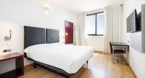 瓦伦西亚伊鲁尼阿夸3号酒店的卧室配有一张白色大床和电视。