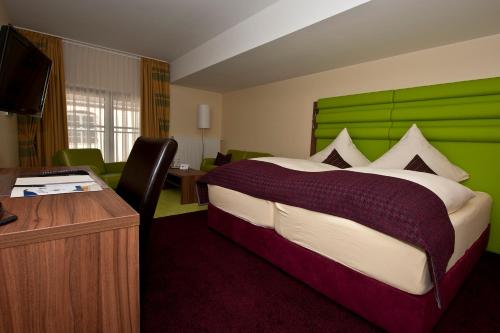 沃尔姆斯安什洛斯帕克别墅酒店的一间卧室配有一张大床和绿色床头板