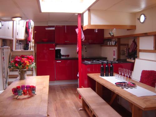莱顿Zeilschip De Vrouw Dina的厨房配有红色橱柜和木桌