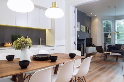 伦敦STUNNING Brand New Apartment的用餐室以及带木桌和白色椅子的客厅。