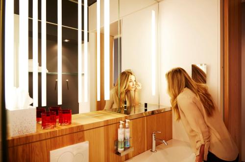温尼伯温尼伯阿尔特酒店 的女人在浴室镜子里看着她的反射