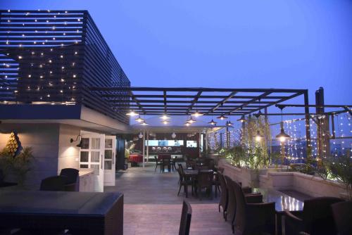 新德里Hotel Picasso Prive Naraina Delhi - Couple Friendly Local IDs Accepted的屋顶露台配有桌椅和灯光