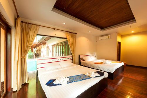 攀牙棕榈山度假村的一间卧室设有两张床和大窗户