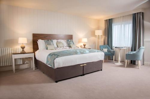邓格洛Waterfront Hotel Dungloe的酒店客房带一张大床和两张椅子