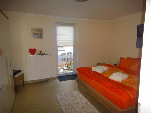 瓦尔内明德Ferienwohnung Nr.31的一间卧室配有带橙色床单的床和窗户。