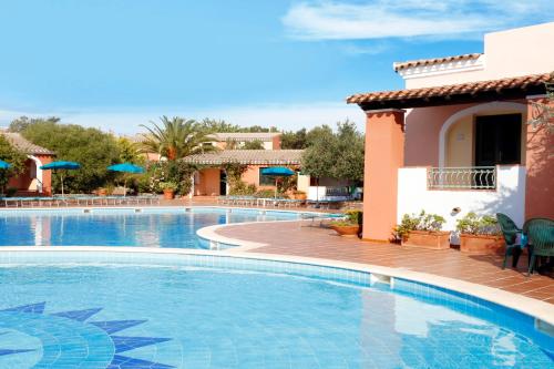 卡拉·利贝罗托Alba Dorata Resort的度假村的游泳池,配有椅子和遮阳伞