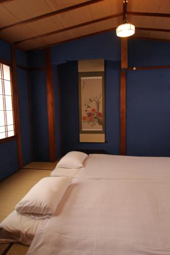 金泽尤卡旅馆的蓝色的客房配有一张带白色枕头的大床
