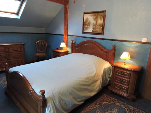 昂德洛老锯木厂度假屋的一间卧室配有一张床、两张桌子和两盏灯。