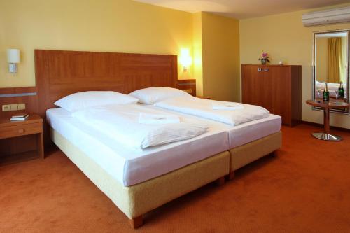 罗斯诺夫·波德·拉德霍斯滕活力康体度假酒店的卧室配有一张带白色床单和枕头的大床。