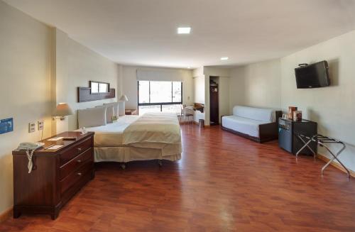 拉巴斯LP哥伦布酒店的一间卧室配有一张床、一张书桌和一台电视。
