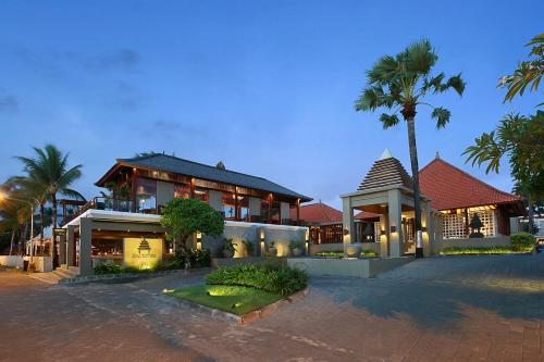勒吉安巴厘尼克莎玛海滩精品度假酒店的一座棕榈树大房子前面