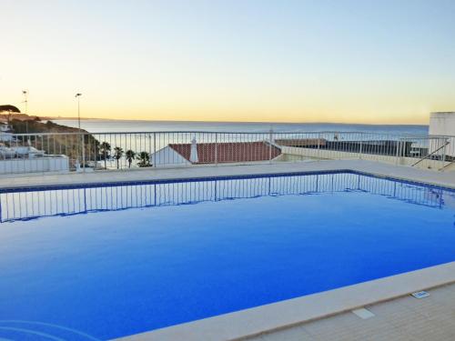 阿尔布费拉Apartamento Olhos D'Água的一个蓝色的大型游泳池,背景是大海