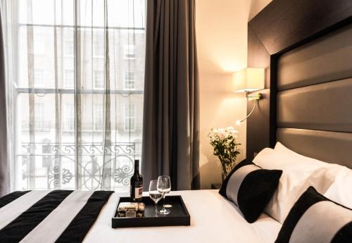 伦敦贝克街公园大道酒店的酒店客房设有床和带酒杯的窗户。
