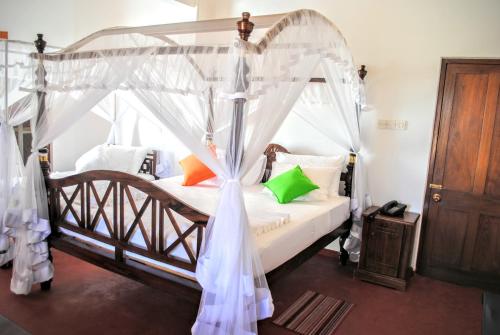 尼甘布缪拉荷兰边缘酒店的卧室配有带白色窗帘的天蓬床