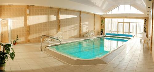 Kozlin金马蹄酒店的一个带椅子和浴缸的大型室内游泳池