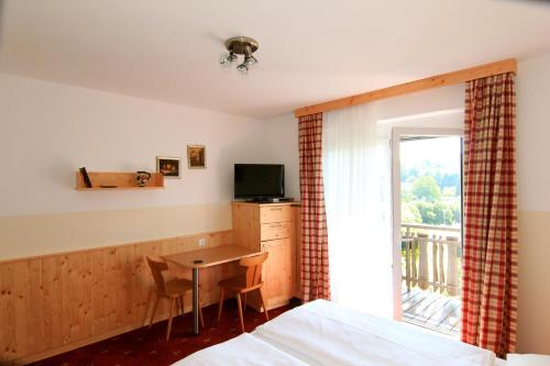 赖弗尼茨Pension Sonnengrund的一间卧室配有一张床和一张书桌及电视