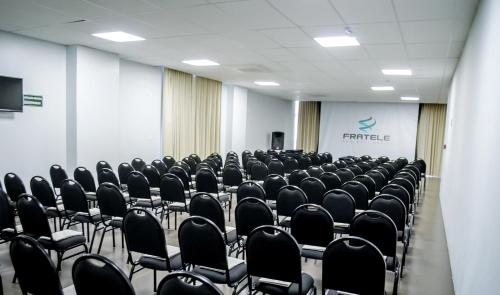 帕图斯迪米纳斯Fratele Business Hotel的一间会议室,配有黑色椅子和屏幕