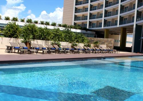 坎昆Krystal Urban Cancun & Beach Club的一座带椅子的游泳池以及一座建筑