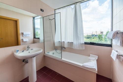 罗马Sotel Nomentana Roma的一间带水槽和浴缸的浴室以及窗户。