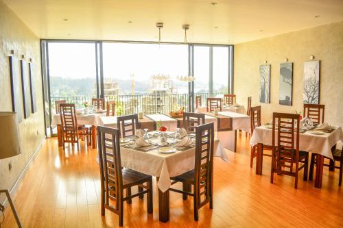 努沃勒埃利耶Highland Stonehouse的用餐室配有桌椅和大窗户
