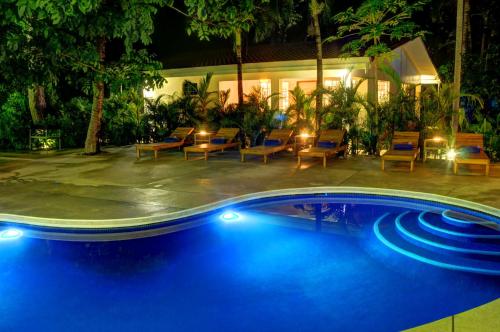 诺萨拉Moana Surf Resort的夜间游泳池,配有桌椅