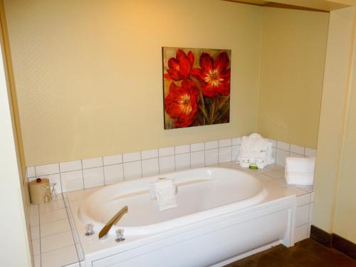 萨塞克斯苏塞克斯阿姆斯特丹套房酒店的浴室配有浴缸,墙上挂有绘画作品